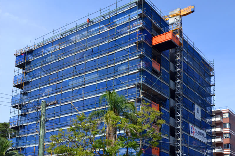 Commercial building undergoing renovation, covered in scaffolding and safety netting
